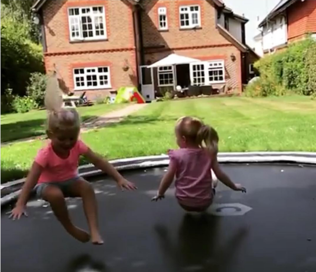 Twins on trampoline in garden